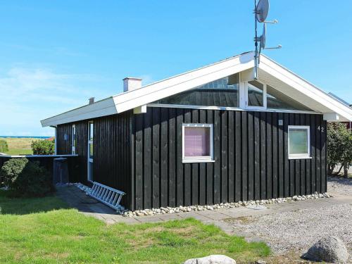 una casa negra con techo blanco en 6 person holiday home in Hadsund, en Øster Hurup