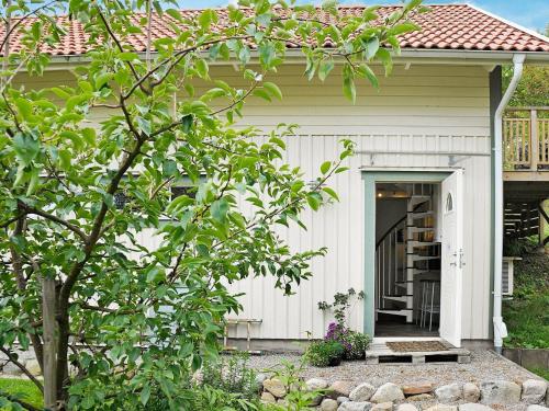 una pequeña casa blanca con porche y puerta en 5 person holiday home in Fj llbacka, en Fjällbacka
