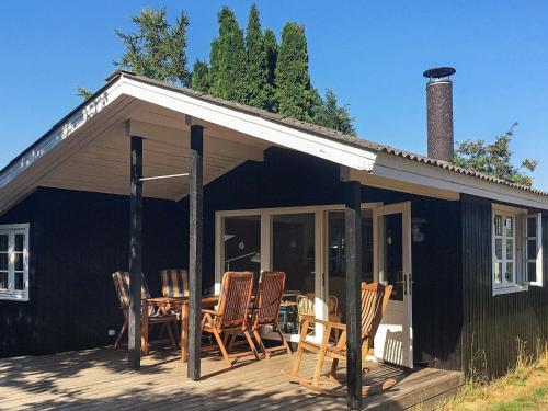 Ce cottage noir dispose d'une terrasse avec une table et des chaises. dans l'établissement 5 person holiday home in Stege, à Stege