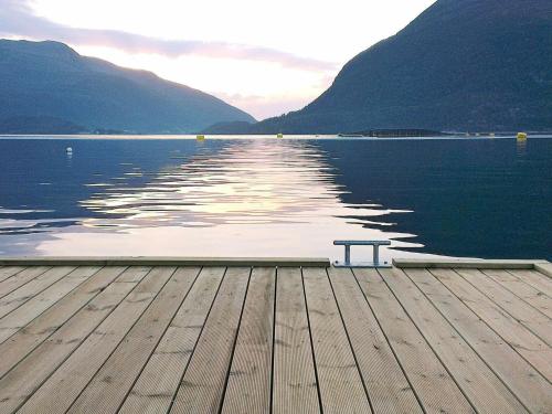 a bench sitting on a dock next to the water at 6 person holiday home in Halsanaustan in Korsnes