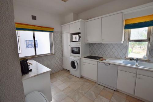 a white kitchen with a sink and a washing machine at Villa Oleander in Vale do Lobo