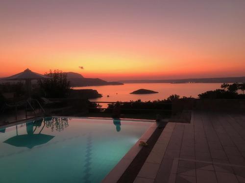 a swimming pool with a sunset in the background at Bliss House Villa in Plaka
