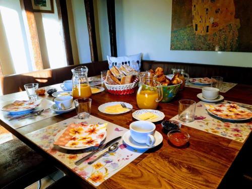 Una mesa de madera con alimentos para el desayuno y jugo de naranja. en La Villonnière, en Parnac