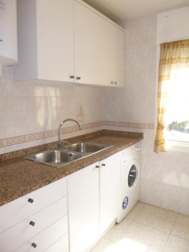 a kitchen with white cabinets and a sink at Leo in L'Estartit