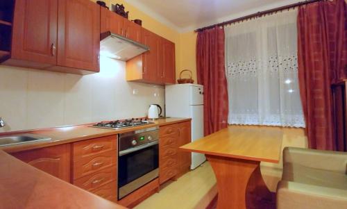 a small kitchen with wooden cabinets and a table in it at Apartament TwojaNoc in Mielec