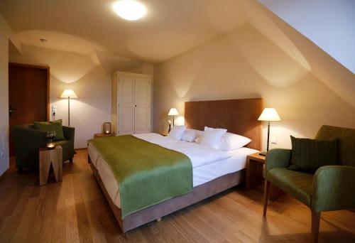 a bedroom with a large bed and two chairs at Weinkastell Zum Weissen Ross in Kallstadt