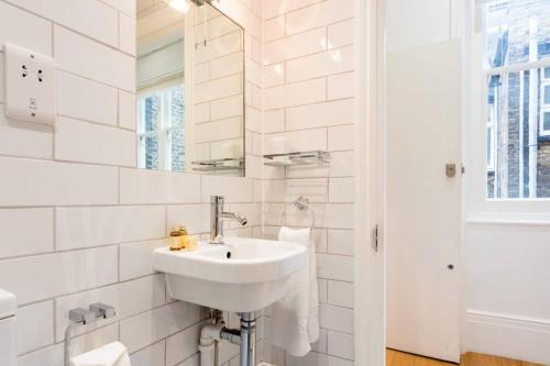 La salle de bains blanche est pourvue d'un lavabo et d'un miroir. dans l'établissement Covent Garden Apartments - Netflix and Nespresso, à Londres