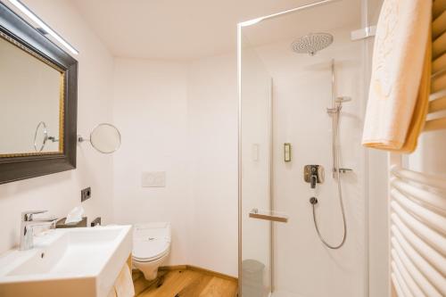 a white bathroom with a shower and a sink at Alpenwellnesshotel St. Veit in Sesto
