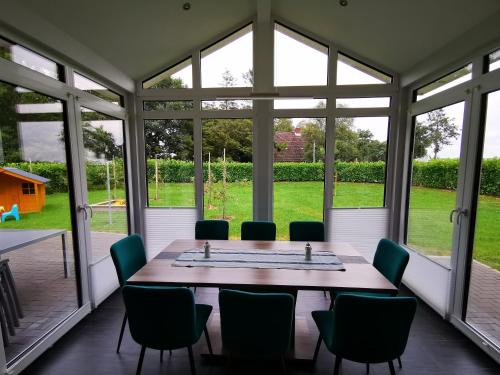 a dining room with a table and chairs and windows at Traumhaftes Ferienhaus an der Nordseeküste in Otterndorf