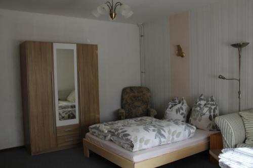 - une chambre avec un lit, un miroir et une chaise dans l'établissement Pension Angelika, à Cottbus