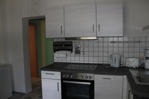 cocina con armarios blancos y fogones en Pension Angelika, en Cottbus