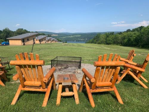 three wooden chairs and a table with a fire pit at Lakeside Resort in Watkins Glen