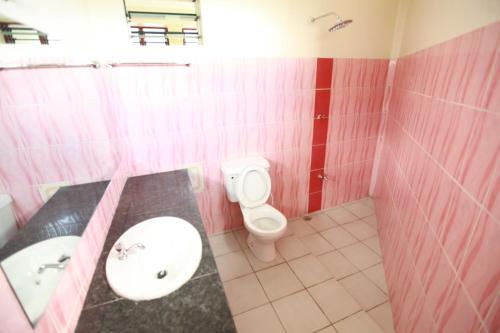 a pink bathroom with a sink and a toilet at Coastgate Hotel in Mombasa