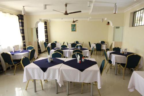 Habitación con varias mesas y sillas, mesas blancas y azules y chairsop. en Coastgate Hotel en Mombasa