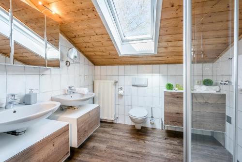 a bathroom with two sinks and a toilet and a skylight at Hochgallinger Hof in Siegsdorf