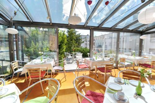 un restaurante con mesas y sillas blancas y ventanas en Abalon Hotel ideal en Stuttgart