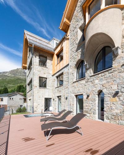a house with two lounge chairs on a wooden deck at Randolins Familienresort in St. Moritz