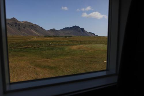 a window with a view of a field and mountains at Aurora Cabins in Höfn