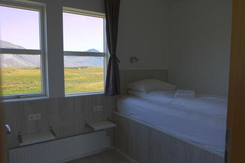 a small bedroom with a bed and two windows at Aurora Cabins in Höfn