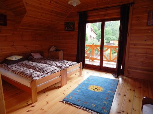 1 dormitorio en una cabaña de madera con cama y ventana en Dom na Roztoczu, en AdamÃ³w