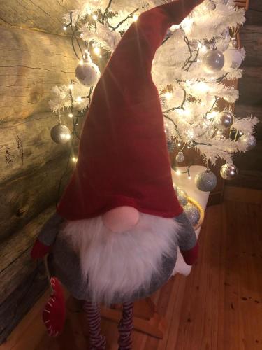 a santa claus doll in front of a christmas tree at Villa Karhuntähti in Luosto