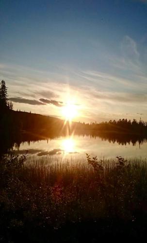 a sunset over a lake with the sun setting at Villa Karhuntähti in Luosto