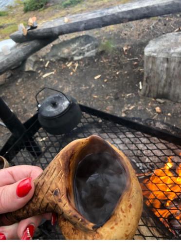 a person holding a wooden spoon over a fire at Villa Karhuntähti in Luosto
