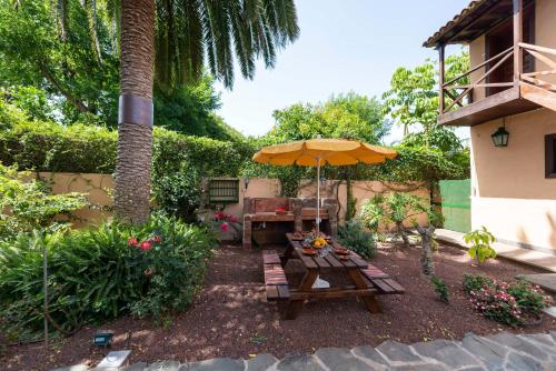 a patio with a table and an umbrella at Rincón de los Abanes - Finca Casa Jardín-VV in Las Lagunas