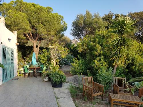 un patio con mesa, sillas y árboles en Casa Prescilia, en Lumio