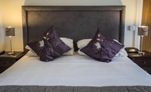 a bed with two purple pillows on top of it at Bayview Farm Holiday Cottages in Bushmills