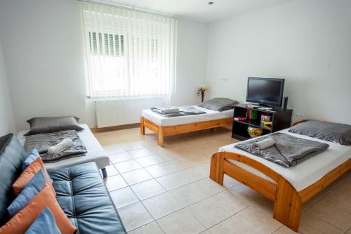 a living room with two beds and a tv at Virágos vendégház in Keszthely