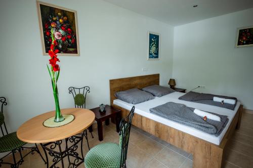 Virágos vendégház في كيزتيلي: غرفة نوم بسرير وطاولة مع إناء من الزهور