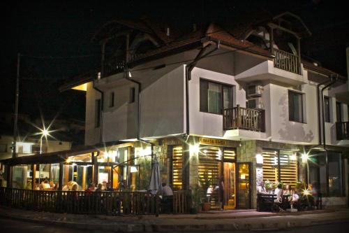 a building with people sitting outside of it at night at Бялата къща in Zlatograd