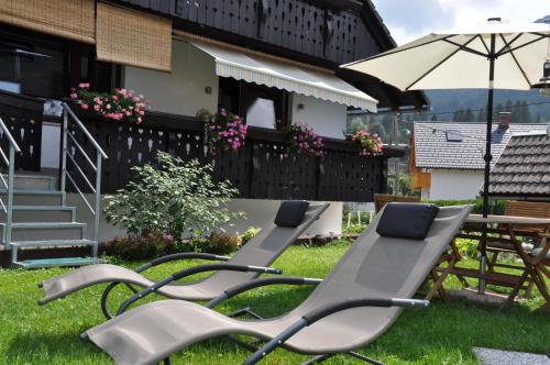 two lounge chairs and an umbrella in a yard at Snežak (Snowman) in Bohinj