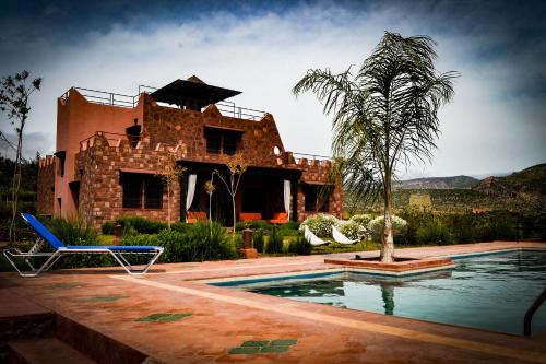 a house with a palm tree and a swimming pool at Les Jardins Yasmina Bin el-Ouidane in Bine el Ouidane