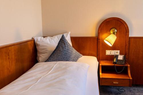 a bedroom with a bed and a phone on a night stand at Parkhotel in Bad Waldsee