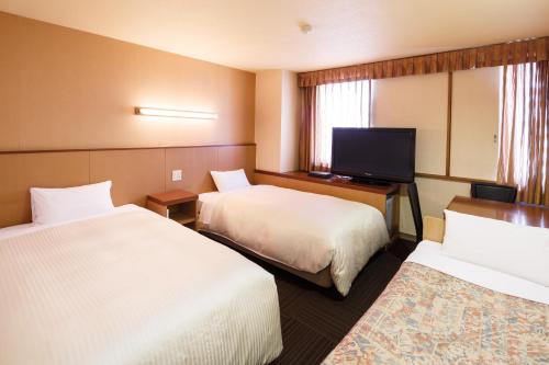 a hotel room with two beds and a flat screen tv at Sunsky Hotel in Kitakyushu