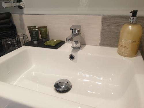 a white bathroom sink with a bottle of wine at Open Acres Accommodation in Bristol
