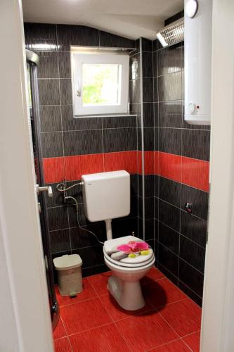 a bathroom with a toilet with a window and black tiles at "DreamHome Mušić" Rasavci in Prijedor