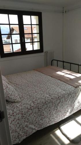 - un lit dans une chambre avec 2 fenêtres dans l'établissement Marinela, à Hendaye