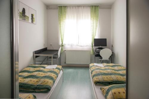 um quarto com 2 camas, uma secretária e uma janela em Hostel M em Maribor