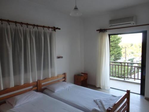 a bedroom with two beds and a window with a balcony at Chris Apartments in Metamorfosi