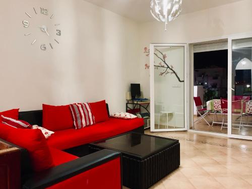 a living room with a red couch and a clock on the wall at Marina Saidia AP8 LILIA in Saïdia