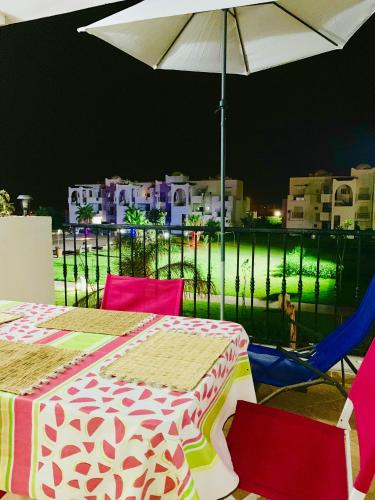 a table and chairs with an umbrella on a balcony at Marina Saidia AP8 LILIA in Saidia 