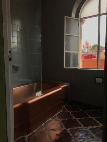 a bathroom with a bath tub and a window at Hotel Galería in San Miguel de Allende