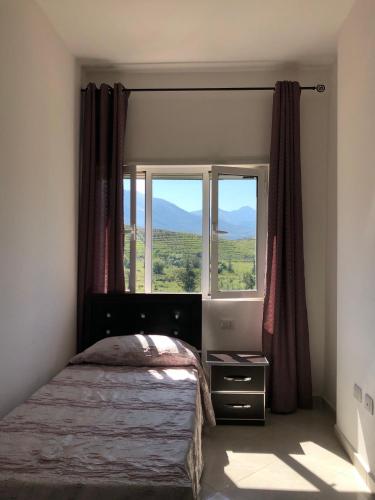 a bedroom with a bed and a large window at Rainbow Holiday Apartments in Vlorë