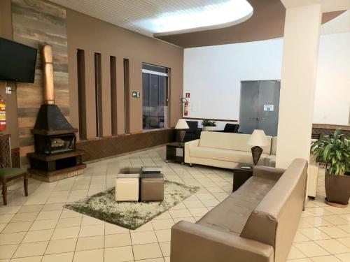 a lobby with a couch and a fireplace in a building at Presidente Hotel in Poços de Caldas