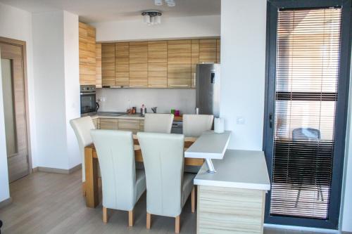 a kitchen with a dining table and white chairs at High End Apartments in Diamond Garden Building in Skopje
