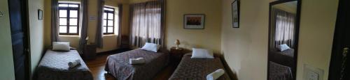 a room with two beds and a couch and windows at El Tuco Hotel in Cusco