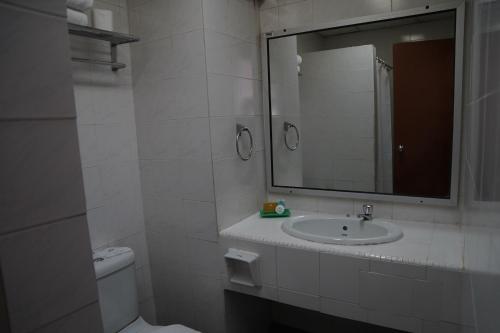 a white bathroom with a sink and a mirror at Hotel Seri Malaysia Johor Bahru in Johor Bahru
